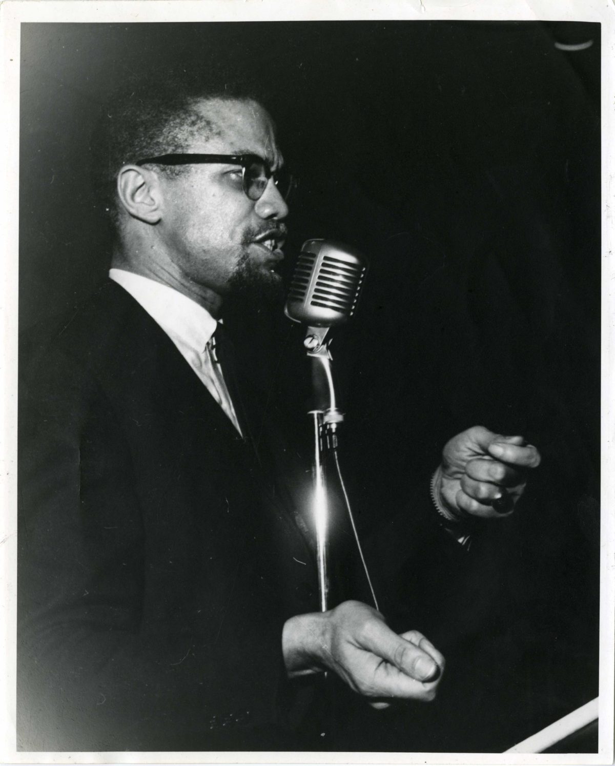 Malcolm X speaks at a microphone