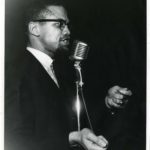 Malcolm X speaks at a microphone