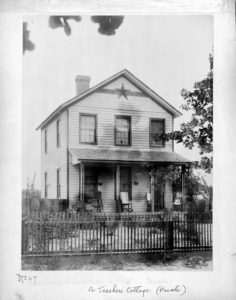 two-story home with a wooden fence, front porch, and small yard